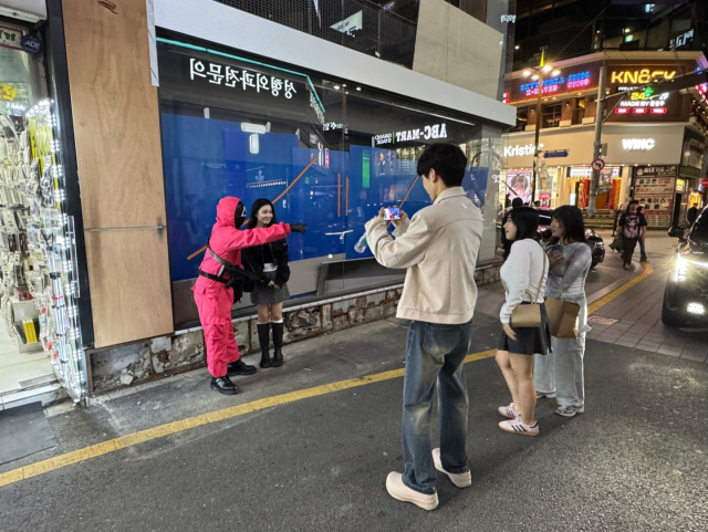 31일 오후 10시께 부산 부산진구 서면 젊음의거리 주변에서 행인들이 '오징어게임' 캐릭터와 사진을 찍고 있다. 손희문 기자