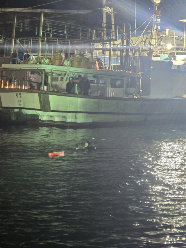 27일 밤 부산 기장군 학리항 차량 추락 사고 현장에서 울산해양경찰서 경찰관들이 침수 차량의 탑승자를 구조하기 위해 수색 작업을 벌이고 있다. 울산해경 제공