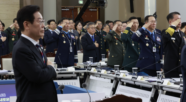 18일 서울 용산구 국방부에서 열린 국방부·국가보훈부 업무보고에서 이재명 대통령을 비롯한 참석자들이 국기에 경례하고 있다. 이날 업무보고에는 진영승 합동참모의장, 김규하 육군참모총장, 강동길 해군참모총장, 손석락 공군참모총장, 주일석 해병대사령관 등이 참석했다. 연합뉴스