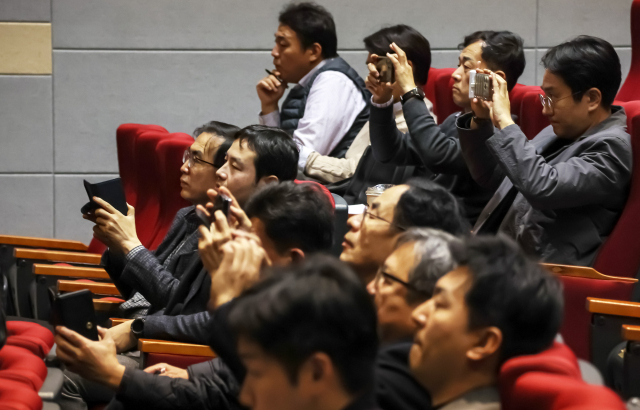 지난해 11월 부산 남구 기술보증기금 별관 대강당에서 열린 가덕도신공항 부지 조성 공사 사업설명회에 건설사 담당자들이 사업 설명 자료를 촬영하고 있다. 김종진 기자 kjj1761@