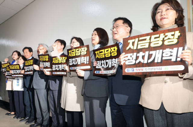 조국혁신당·진보당·기본소득당·사회민주당 등 진보 4당이 19일 국회 정치개혁특위 회의장 앞에서 정치개혁을 촉구하며 손팻말을 들고 구호를 외치고 있다. 연합뉴스