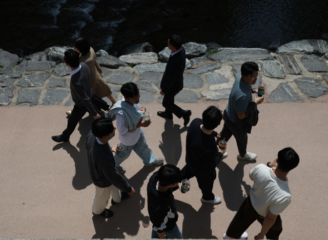 서울의 낮 최고기온이 25도까지 오르는 등 때 이른 초여름 날씨를 보인 13일 서울 청계천을 찾은 시민들이 아이스아메리카노 등 음료수를 들고 이동하고 있다. 연합뉴스