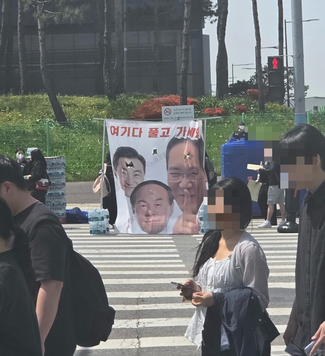 삼성전자 노동조합이 23일 평택사업장 앞에서 대규모 투쟁결의대회를 연 가운데 노조원들이 경영진을 조롱하는 현수막 앞을 지나고 있다. 독자 제공.