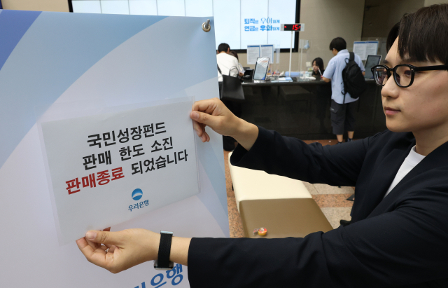 국민참여성장펀드 가입 첫날인 22일 서울 중구 우리은행 본점 영업점에서 한 직원이 한도소진으로 인한 판매종료 안내문을 붙이고 있다. 연합뉴스