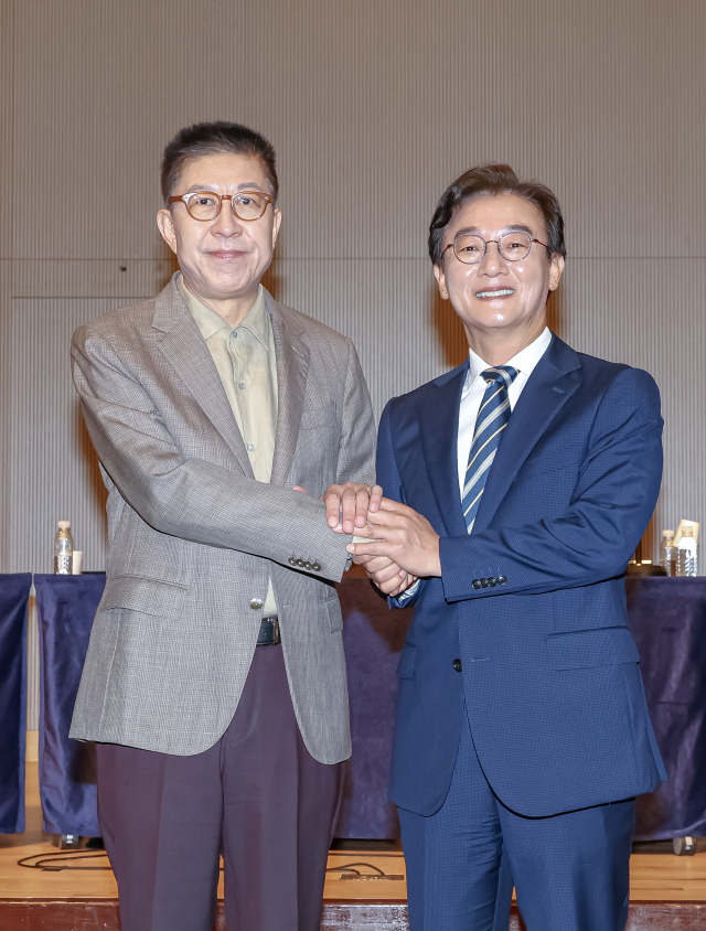 더불어민주당 전재수(오른쪽)·국민의힘 박형준 부산시장 후보가 26일 동서대 센텀켐퍼스에서 열린 관훈클럽·부산일보 초청 토론회 중 손을 맞잡고 있다. 김종진 기자 kjj1761@