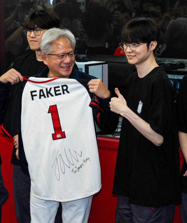 엔비디아 젠슨 황 최고경영자(CEO)가 5일 서울 마포구 T1베이스 캠프에서 ‘페이커’ 이상혁을 비롯한 e스포츠 구단 T1의 리그 오브 레전드(LoL) 선수단을 만나 페이커'의 사인이 담긴 기념품을 선물 받고 있다. 연합뉴스