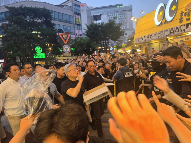엔비디아 젠슨 황 CEO가 5일 서울 마포구 한 삼겹살 식당에서 진행된 회동 중간에 SK하이닉스가 만든 HBM칩스를 시민들에게 나눠주고 있다. 유승호 기자