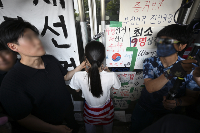 6·3 지방선거 투표용지 부족 사태로 시작한 서울 송파구 올림픽공원 핸드볼경기장 일대 '개표소 봉쇄 시위'가 이어지는 가운데 16일 한 시위 참가자가 대한체육회 등 입주 단체 관계자들의 진입을 막아서고 있다. 연합뉴스